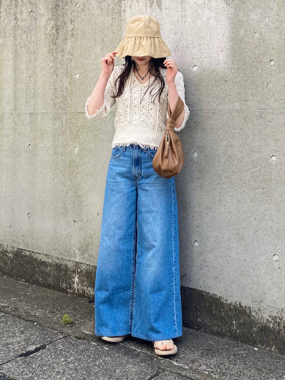 ホワイト系のニット/セーター、ブルー系のデニムパンツ、ブラウン系のバッグを着用したレディースの春コーディネートの2枚目の写真