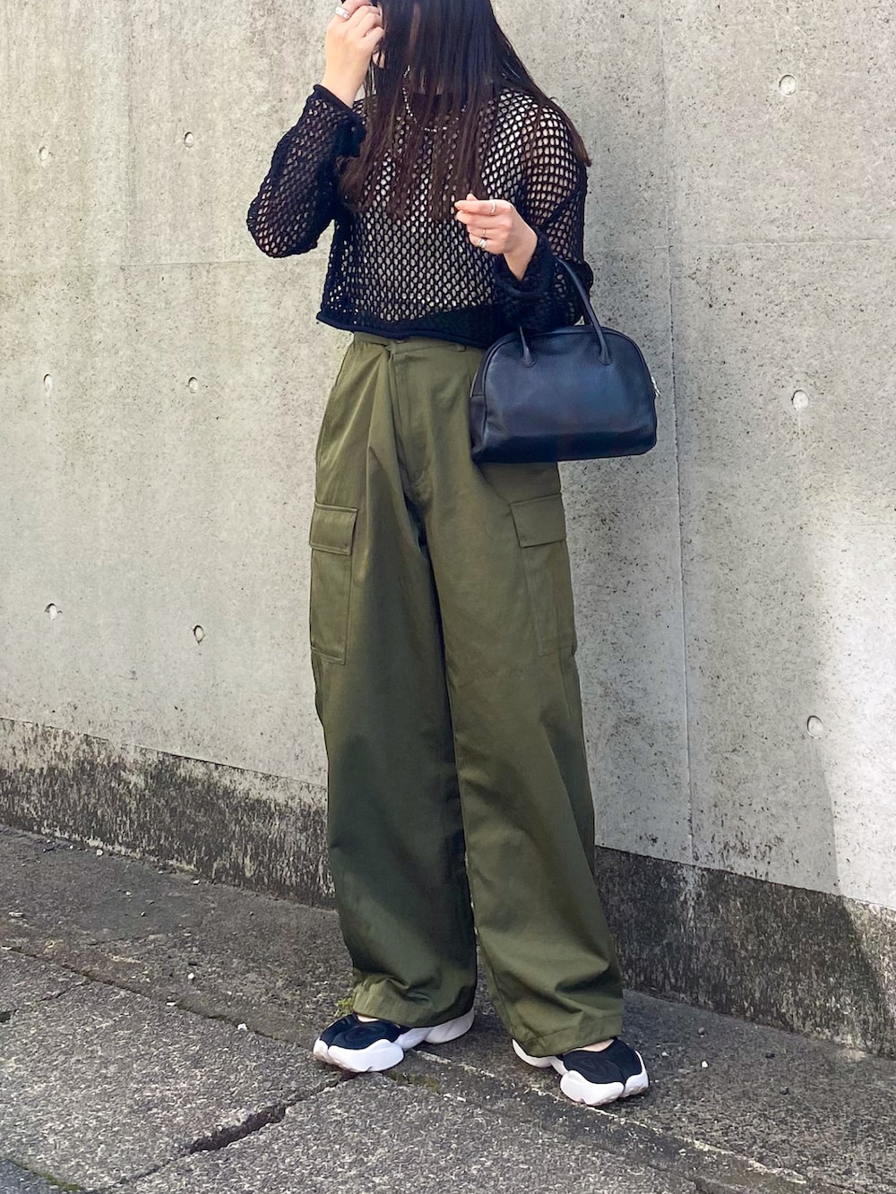 ブラック系のニット/セーター、グリーン系のパンツ、ブラック系のショルダーバッグを着用したレディースの夏コーディネートの2枚目の写真