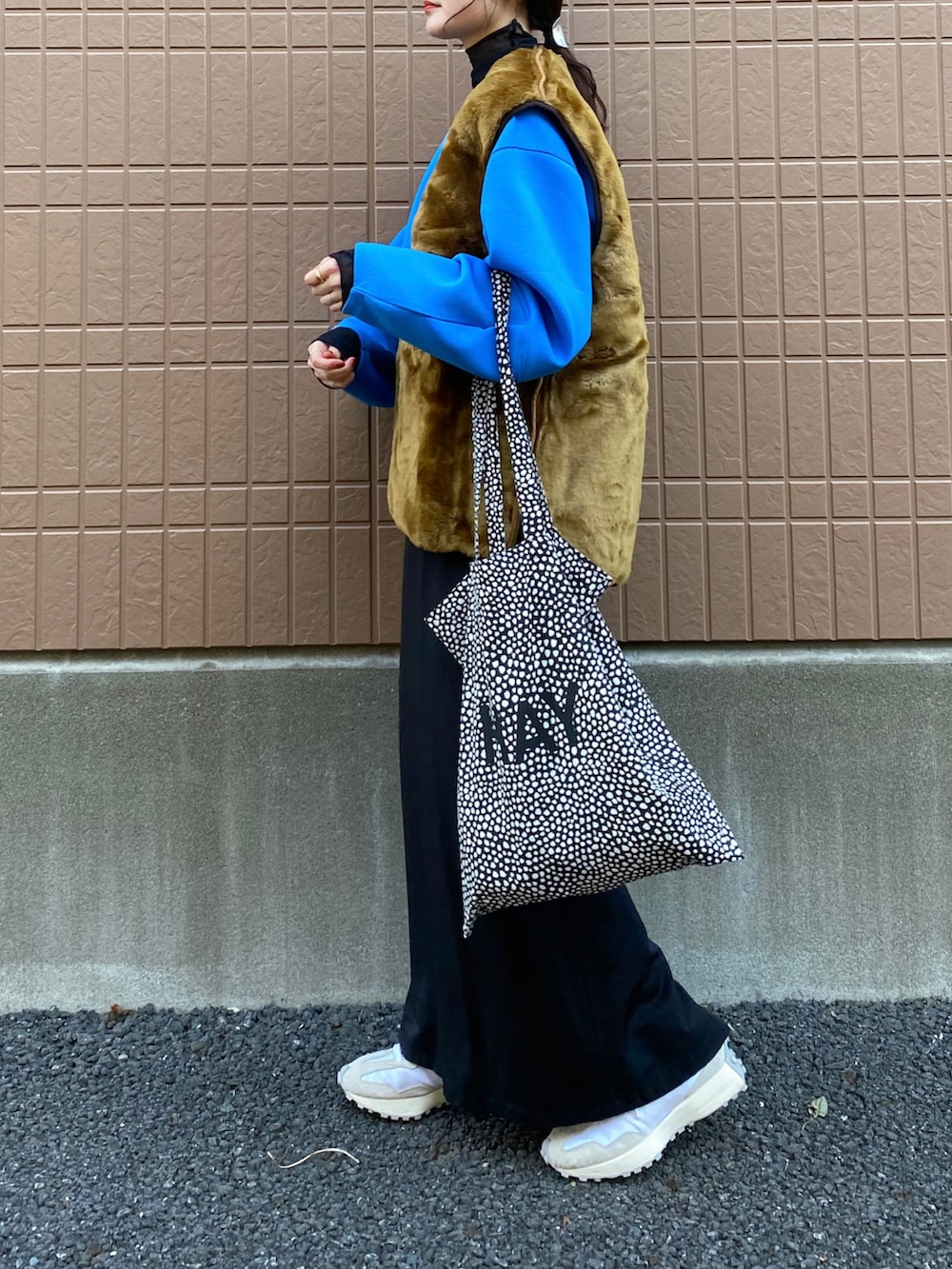 ブラウン系のベスト、ブルー系のニット/セーター、ホワイト系のスニーカーを着用したレディースの冬コーディネートの2枚目の写真