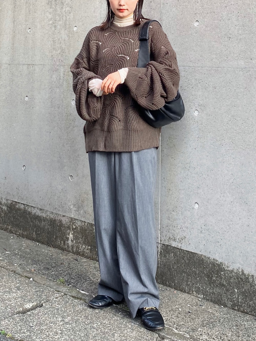 グリーン系のニット/セーター、グレー系のスラックス、ブラック系のショルダーバッグを着用したレディースの秋コーディネートの4枚目の写真