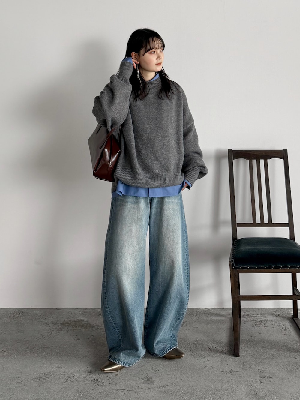 グレー系のニット/セーター、ブラウン系のボストンバッグ、ブルー系のシャツ/ブラウスを着用したレディースの冬コーディネートの2枚目の写真