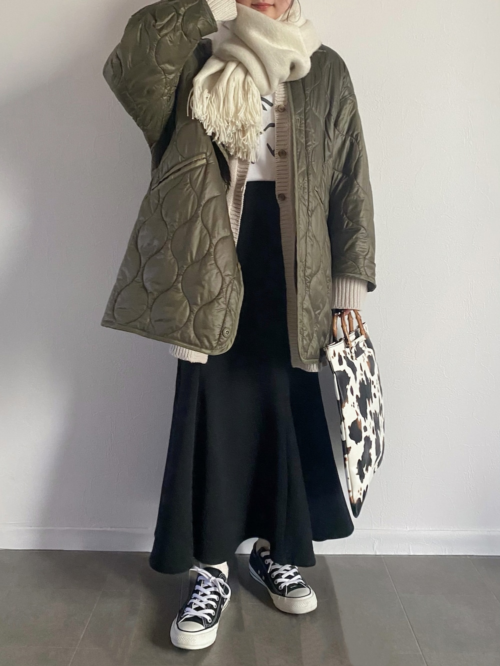 グリーン系のノーカラージャケット、グレー系のニット/セーター、ブラック系のスカートを着用したレディースの冬コーディネートの2枚目の写真