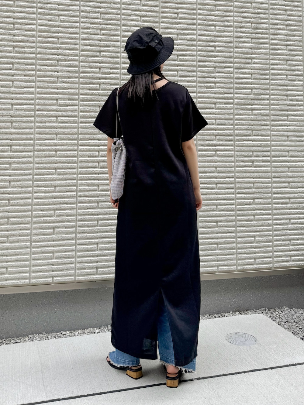 ブラック系のワンピース、ブルー系のデニムパンツ、シルバー系のショルダーバッグを着用したレディースの春コーディネートの3枚目の写真