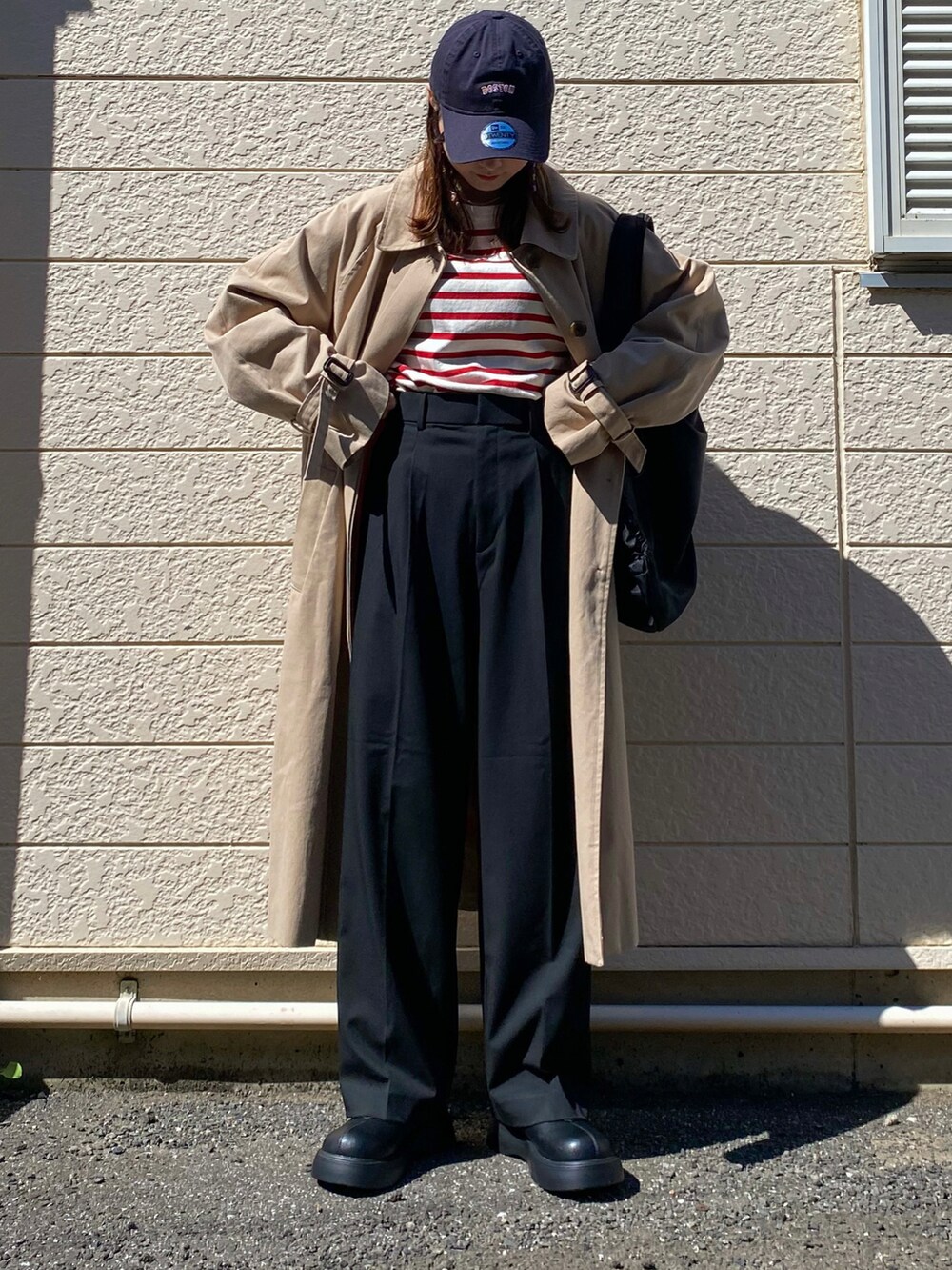 レッド系のTシャツ/カットソー、ブラック系のスラックス、ブラック系のトートバッグを着用したレディースの秋コーディネートの3枚目の写真