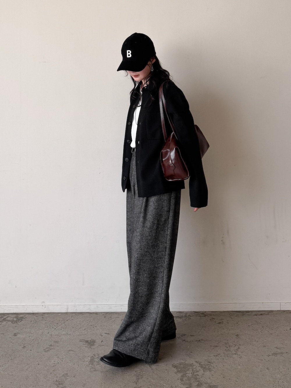 グレー系のスラックス、ホワイト系のTシャツ/カットソー、ブラック系のカーディガン/ボレロを着用したレディースの冬コーディネートの3枚目の写真