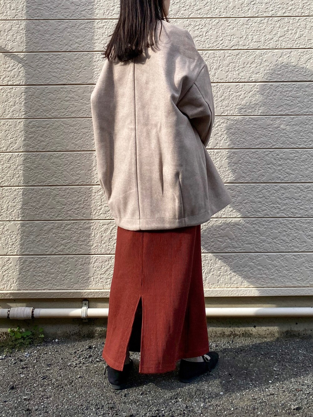 ピンク系のノーカラーコート、ブラウン系のワンピース、ブラック系のショルダーバッグを着用したレディースの秋コーディネートの3枚目の写真