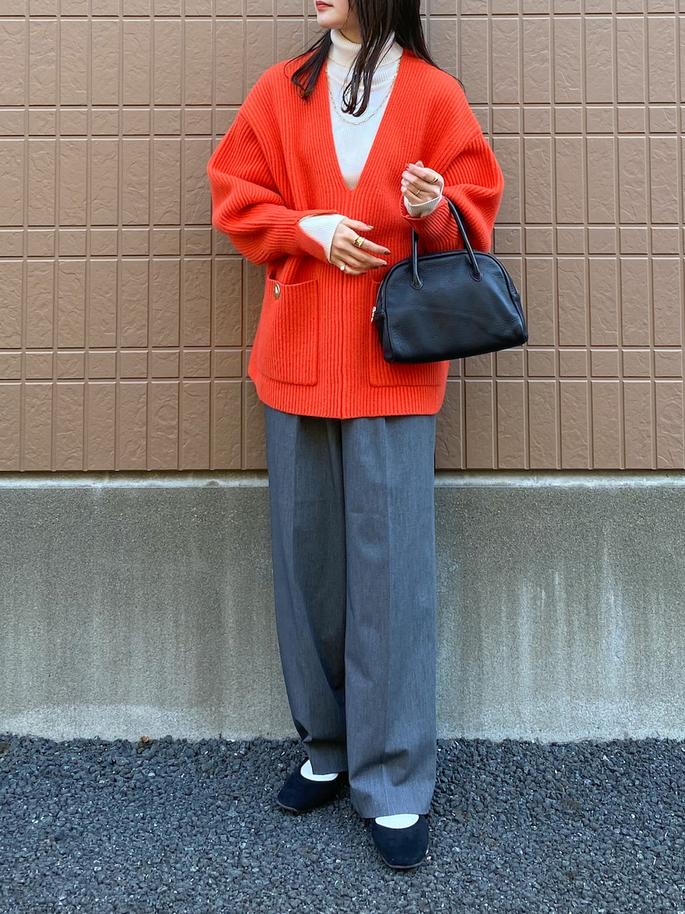 レッド系のニット/セーター、ホワイト系のニット/セーター、グレー系のスラックスを着用したレディースの冬コーディネートの2枚目の写真