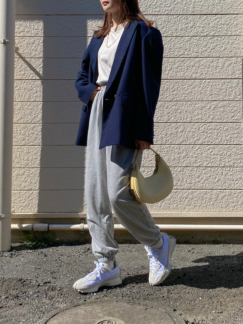 グレー系のスウェットパンツ、ブルー系のテーラードジャケット、イエロー系のハンドバッグを着用したレディースの秋コーディネートの2枚目の写真