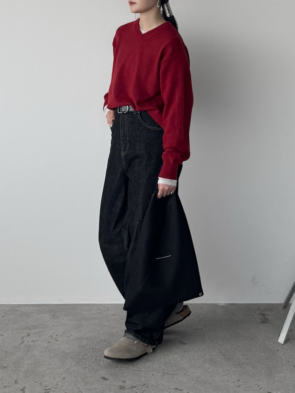ブラック系のデニムパンツ、レッド系のニット/セーター、ホワイト系のTシャツ/カットソーを着用したレディースの秋コーディネートの2枚目の写真