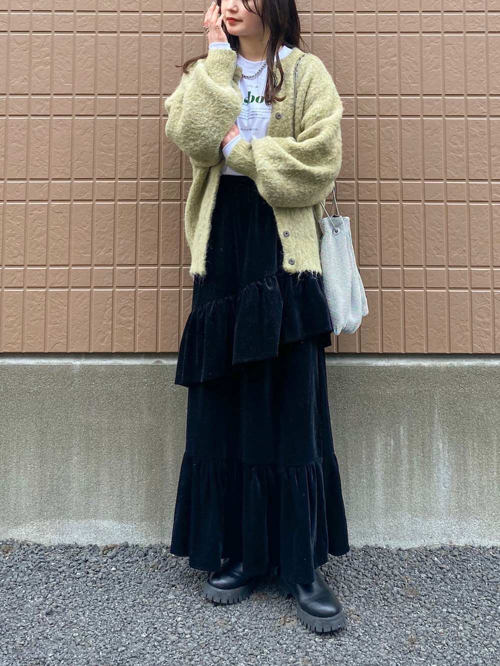 グリーン系のカーディガン/ボレロ、ホワイト系のTシャツ/カットソー、ブラック系のスカートを着用したレディースの春コーディネートの2枚目の写真