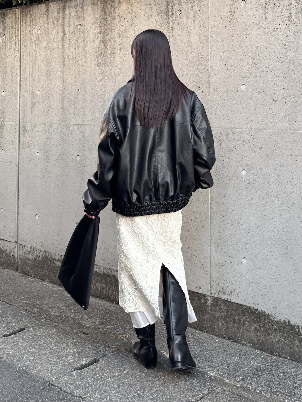 ブラック系のブルゾン、ブラック系のカーディガン/ボレロ、ホワイト系のスカートを着用したレディースの冬コーディネートの2枚目の写真