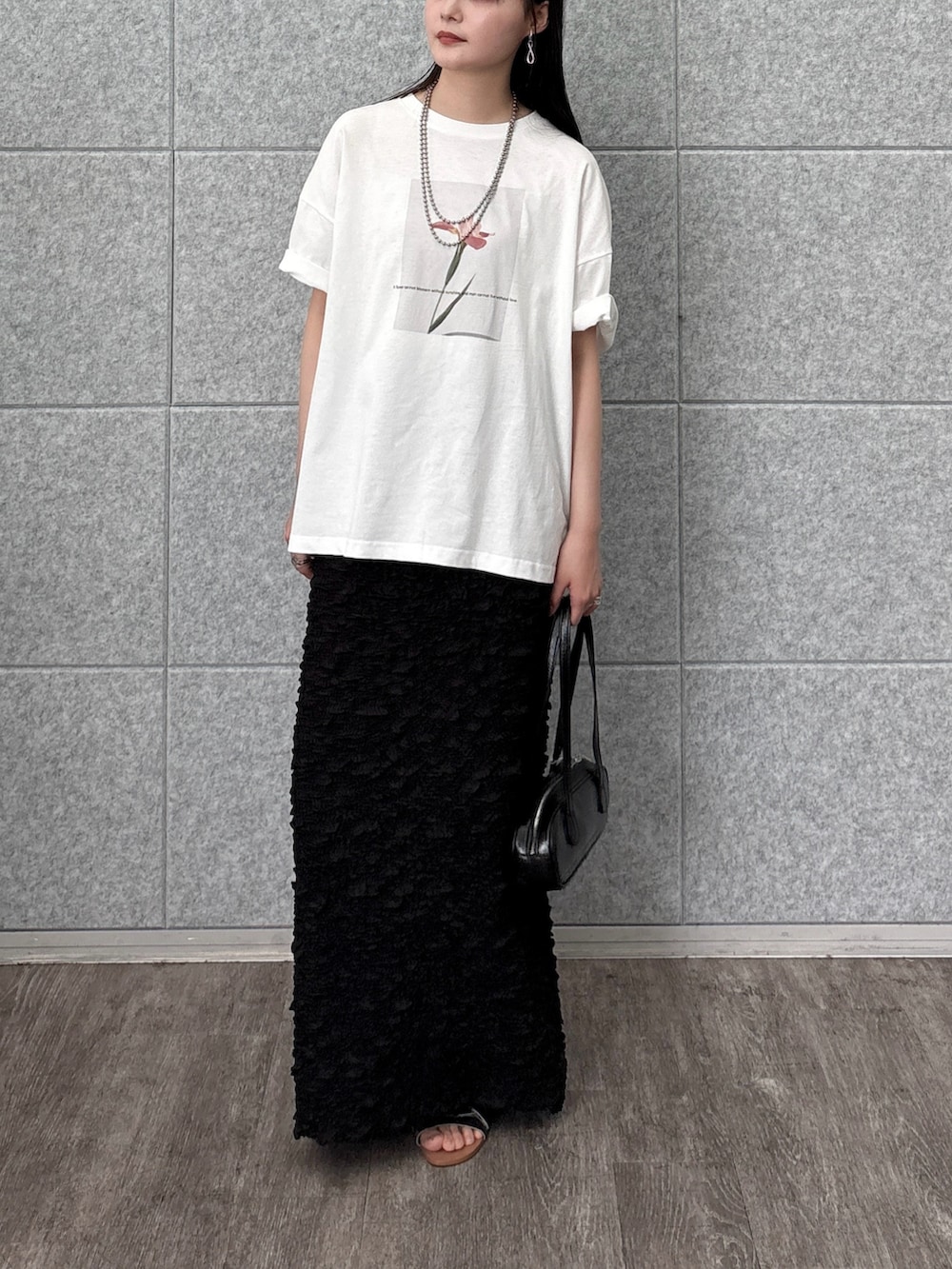 ブラック系のスカート、ホワイト系のTシャツ/カットソー、ブラック系のハンドバッグを着用したレディースの夏コーディネートの3枚目の写真