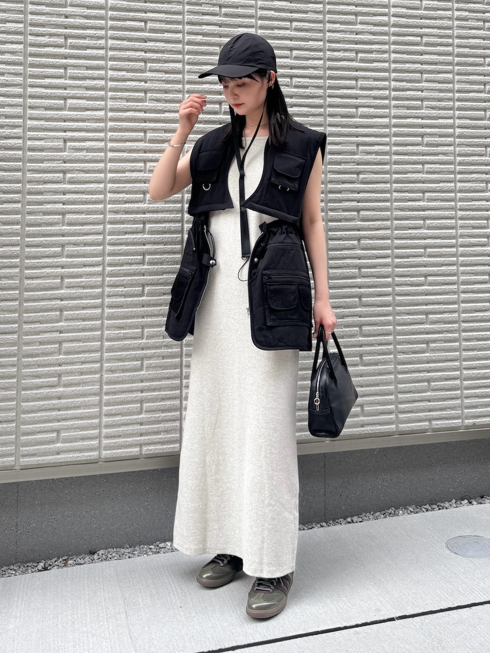 ベージュ系のワンピース、ブラック系のベスト、ブラック系のショルダーバッグを着用したレディースの夏コーディネートの2枚目の写真