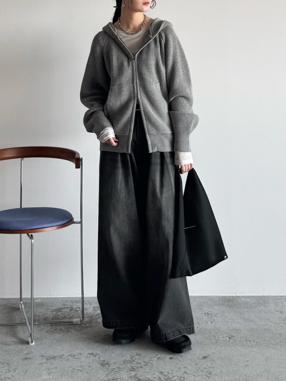 ホワイト系のTシャツ/カットソー、グレー系のニット/セーター、ブラック系のデニムパンツを着用したレディースの秋コーディネートの2枚目の写真