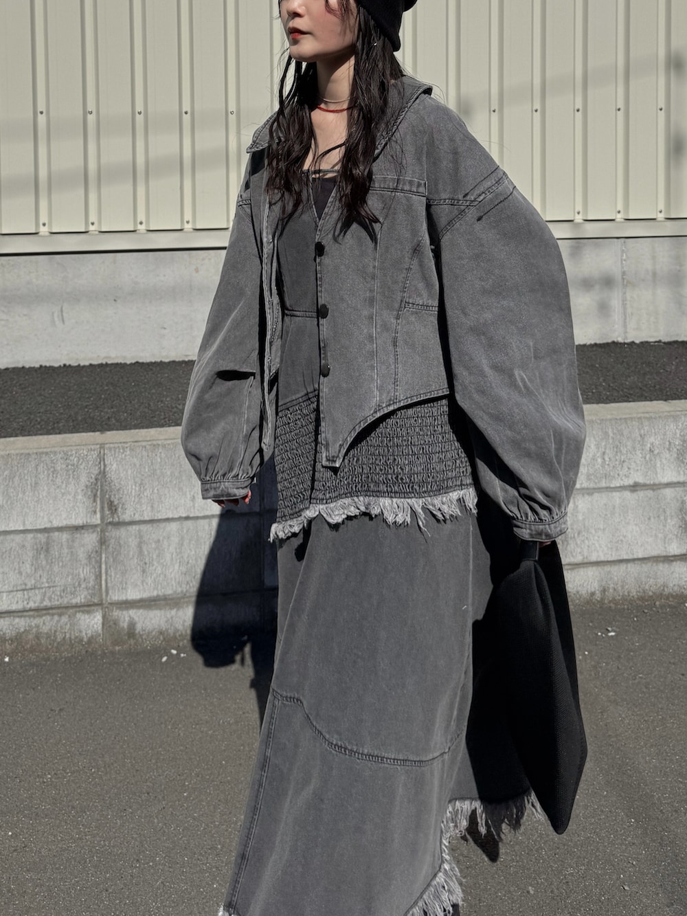 グレー系のデニムジャケット、グレー系のワンピース、ブラック系のブーツを着用したレディースの春コーディネートの2枚目の写真