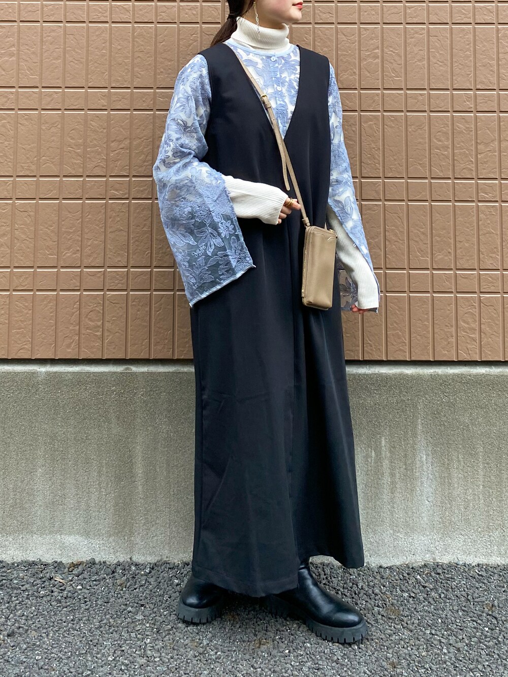 グレー系のシャツ/ブラウス、ブラック系のジャンパースカート、ホワイト系のニット/セーターを着用したレディースの冬コーディネートの2枚目の写真