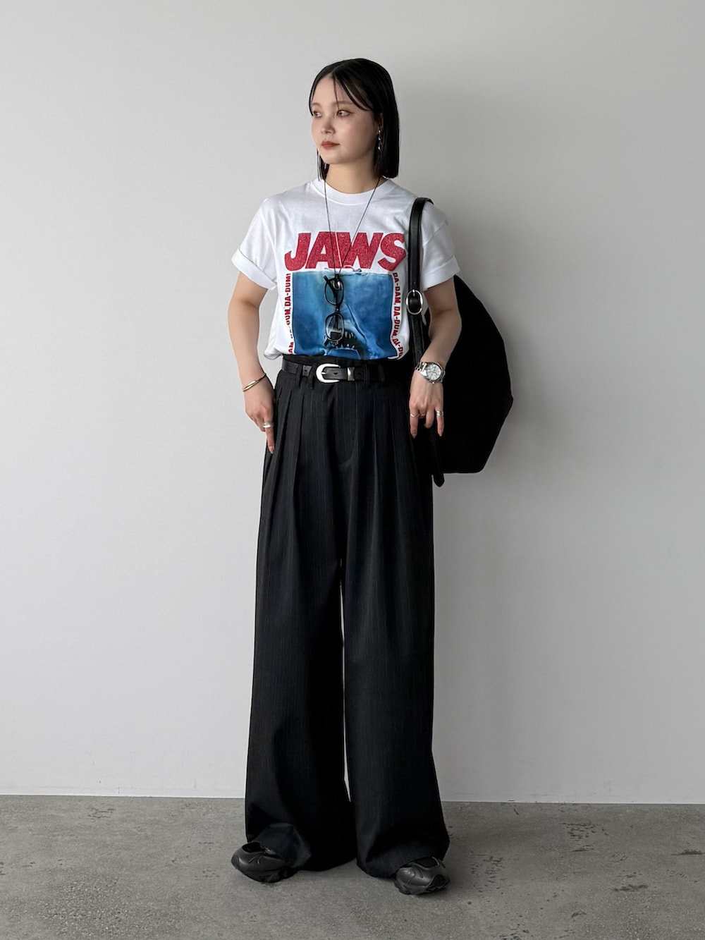 ホワイト系のTシャツ/カットソー、グレー系のスラックス、ブラック系のショルダーバッグを着用したレディースの夏コーディネートの2枚目の写真