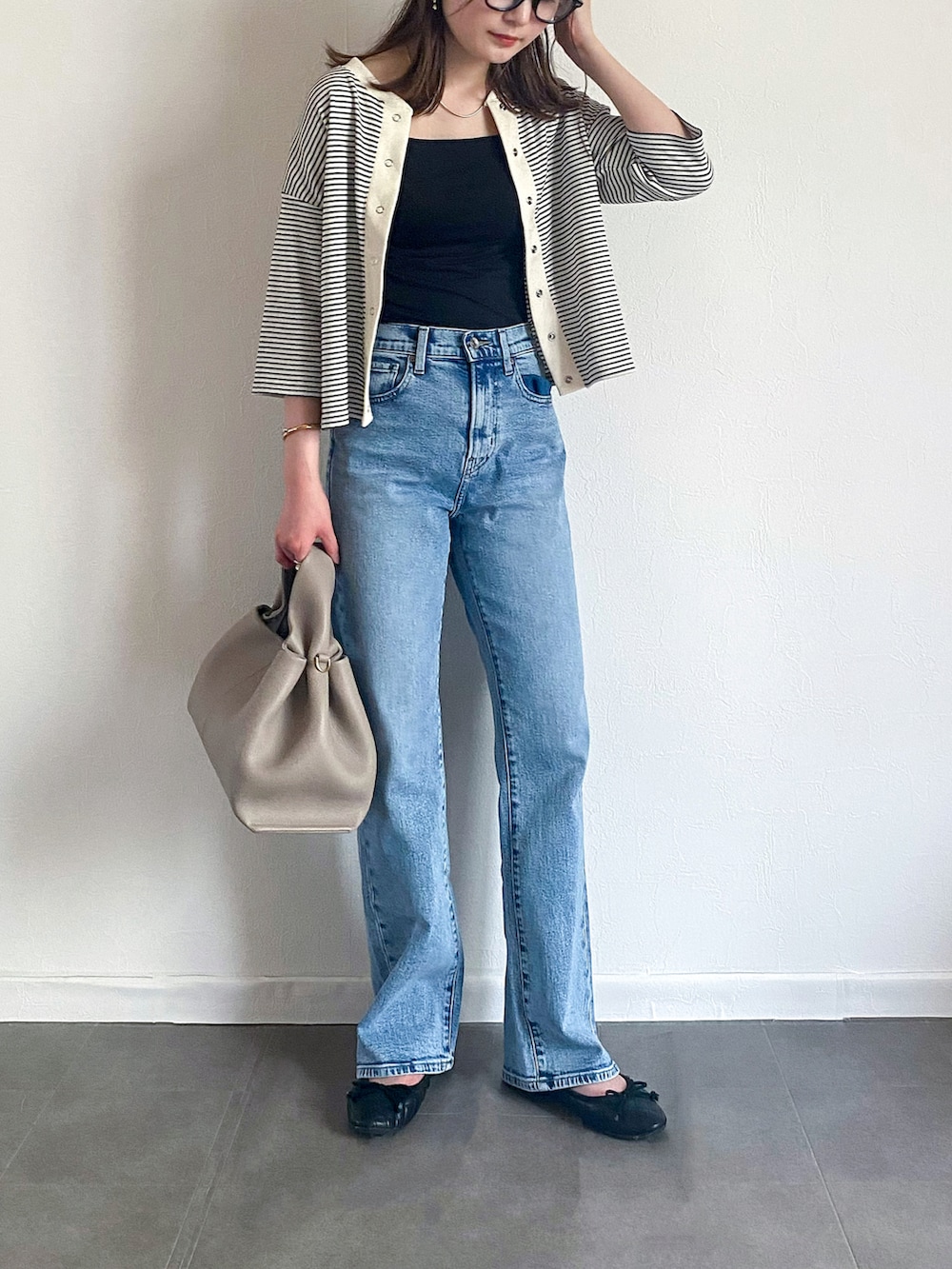 ホワイト系のアンサンブル、ブルー系のデニムパンツ、グレー系のバッグを着用したレディースの夏コーディネートの2枚目の写真