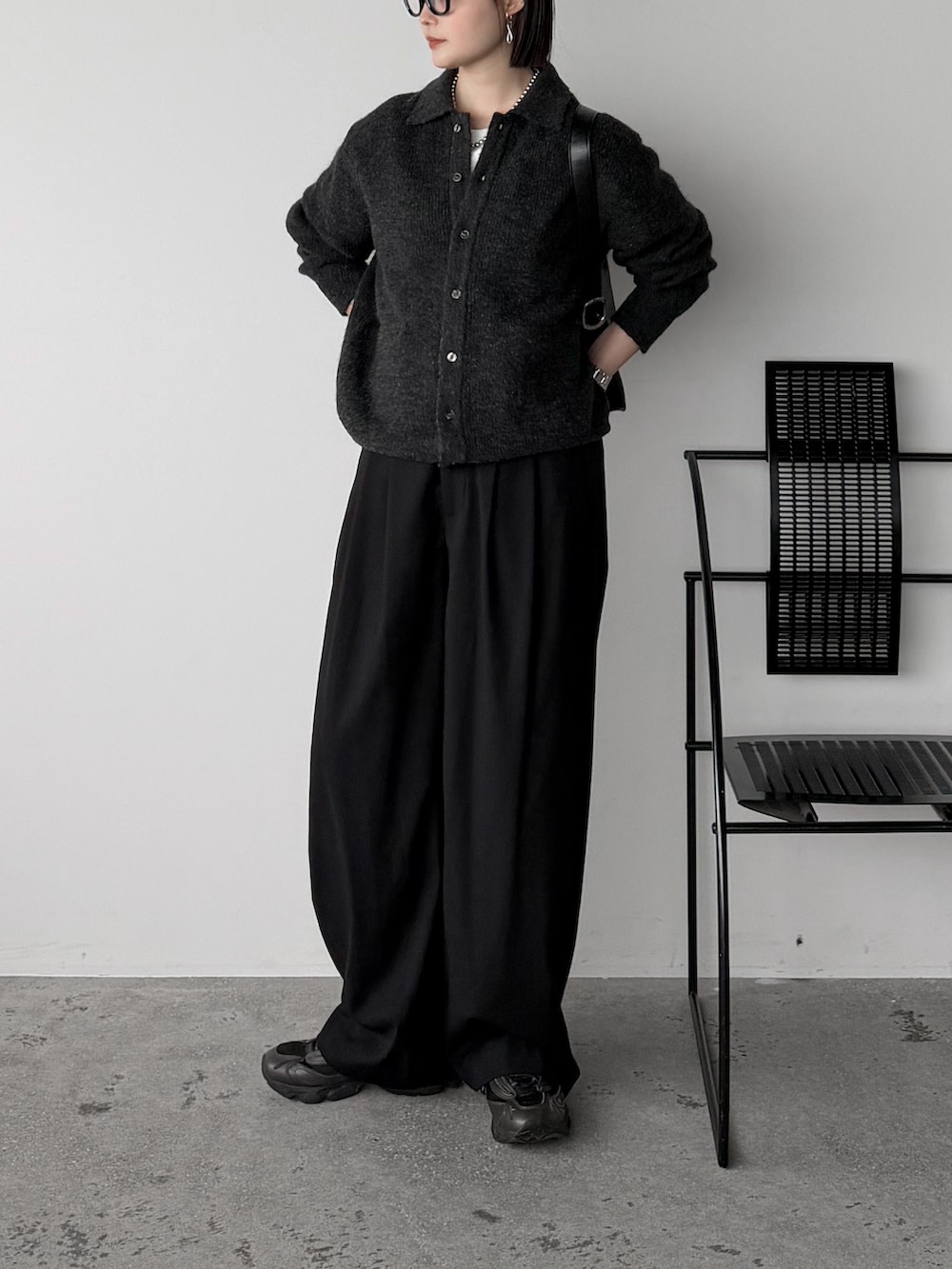 グレー系のニット/セーター、ホワイト系のTシャツ/カットソー、ブラック系のスラックスを着用したレディースの秋コーディネートの2枚目の写真
