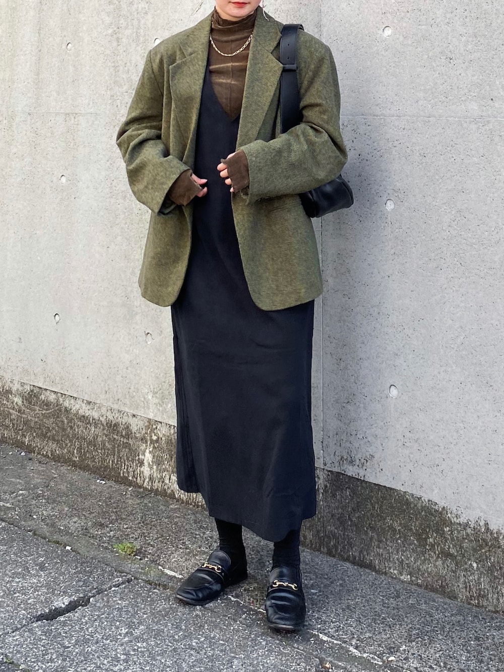 ブラック系のジャンパースカート、グリーン系のテーラードジャケット、ブラウン系のTシャツ/カットソーを着用したレディースの秋コーディネートの3枚目の写真