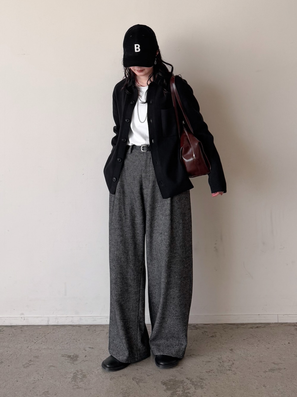 グレー系のスラックス、ホワイト系のTシャツ/カットソー、ブラック系のカーディガン/ボレロを着用したレディースの冬コーディネートの2枚目の写真