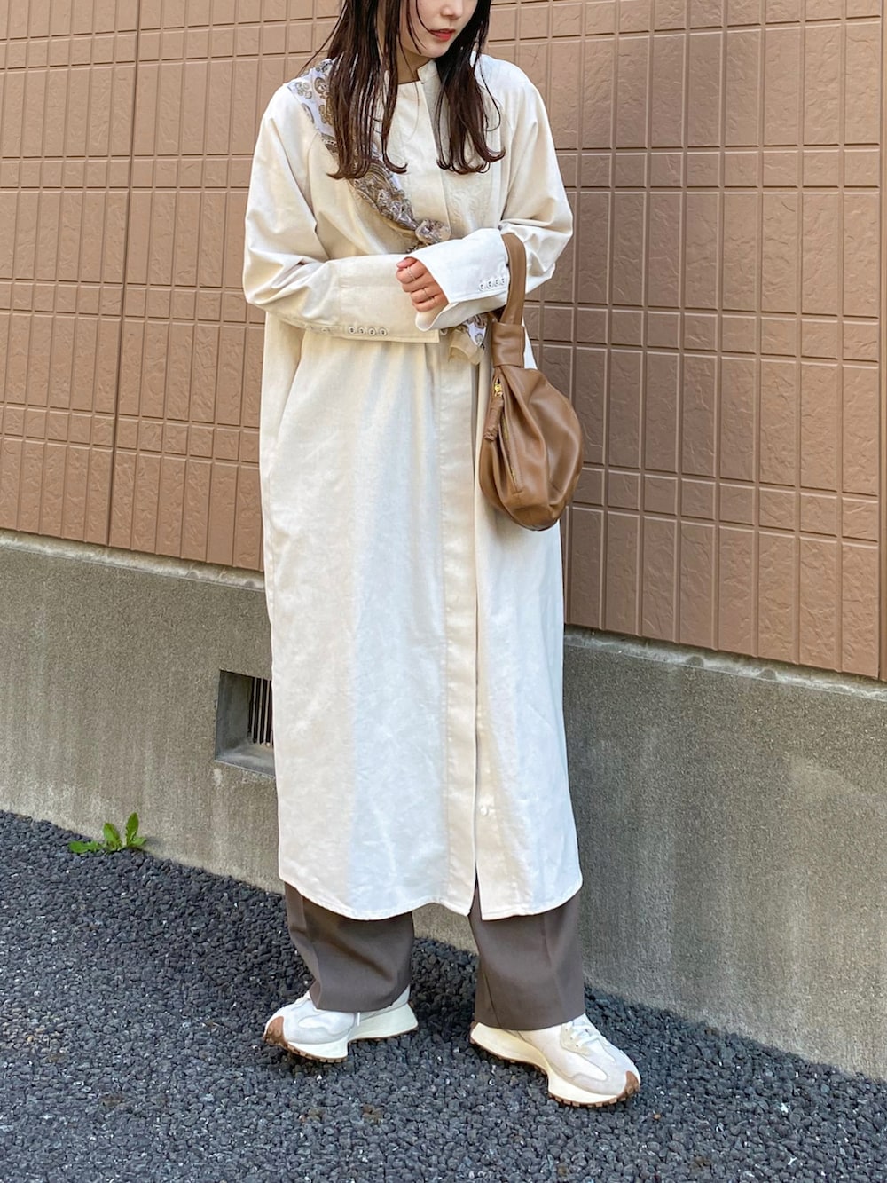 ブラウン系のスラックス、ブラウン系のバッグ、ホワイト系のスニーカーを着用したレディースの春コーディネートの3枚目の写真