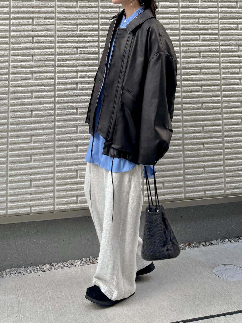 ブラウン系のブルゾン、グレー系のスウェットパンツ、ブラック系のモカシン/デッキシューズを着用したレディースの秋コーディネートの2枚目の写真