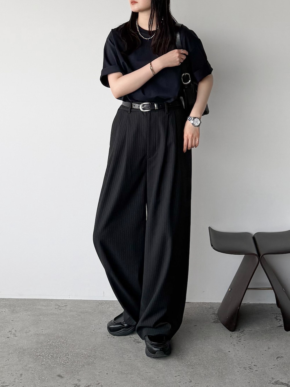 ブラック系のショルダーバッグ、ブルー系のTシャツ/カットソー、グレー系のスラックスを着用したレディースの春コーディネートの2枚目の写真