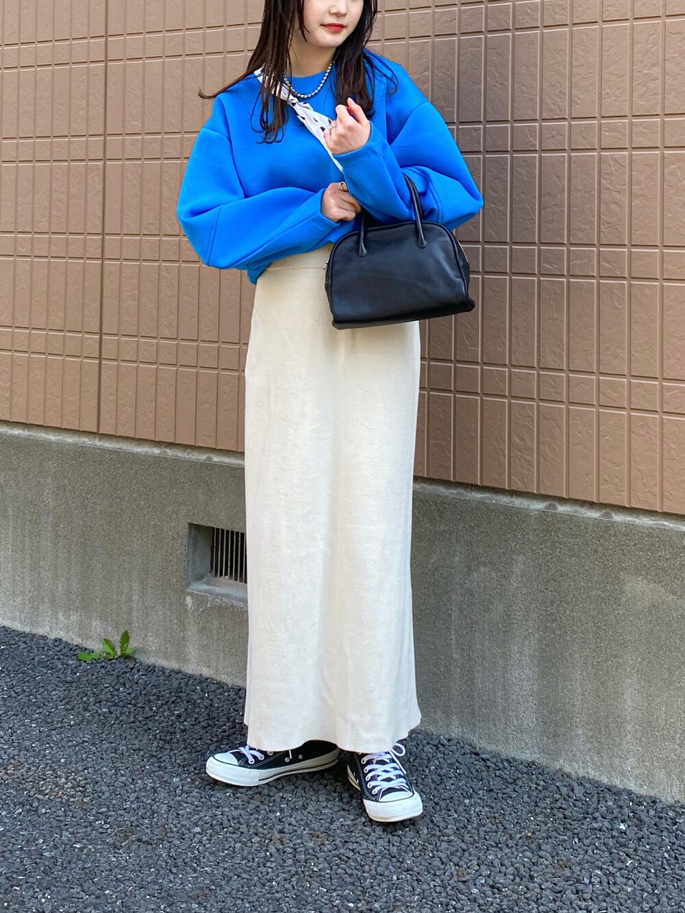 ブルー系のニット/セーター、ホワイト系のスカート、ブラック系のショルダーバッグを着用したレディースの春コーディネートの3枚目の写真