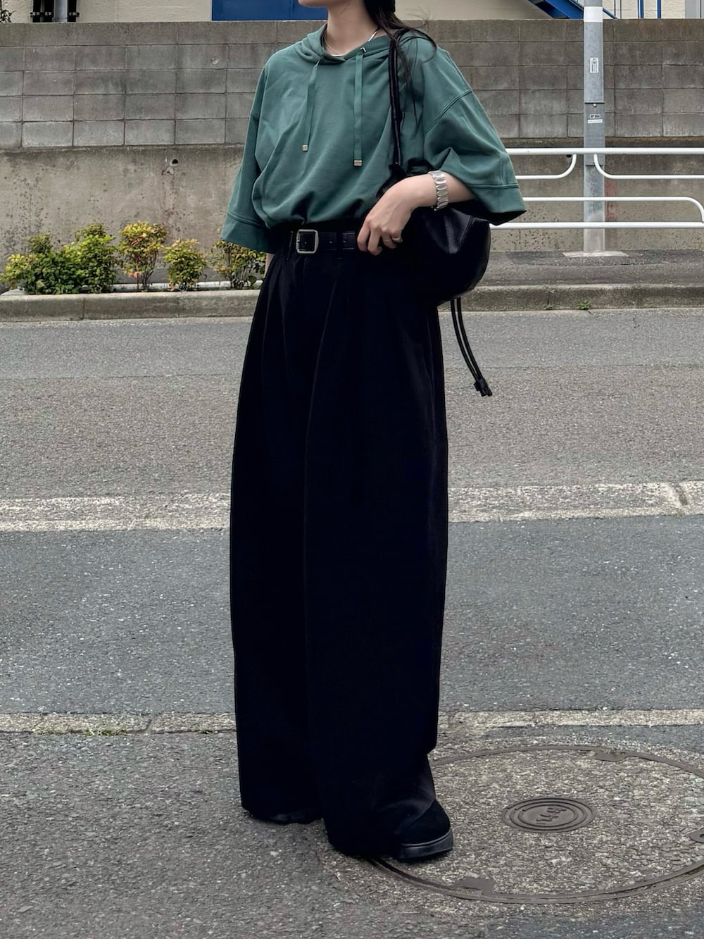 グリーン系のパーカー、ブラック系のスラックス、ブラック系のショルダーバッグを着用したレディースの夏コーディネートの2枚目の写真