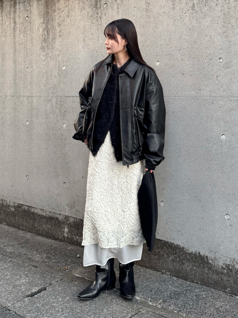 ブラック系のブルゾン、ブラック系のカーディガン/ボレロ、ホワイト系のスカートを着用したレディースの冬コーディネートの3枚目の写真