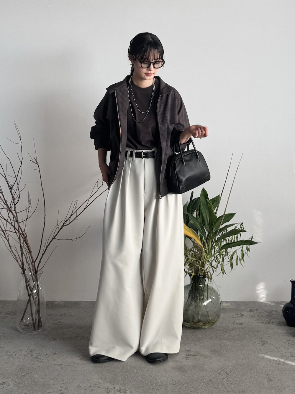 ブラウン系のTシャツ/カットソー、ブラウン系のブルゾン、ホワイト系のスラックスを着用したレディースの秋コーディネートの2枚目の写真