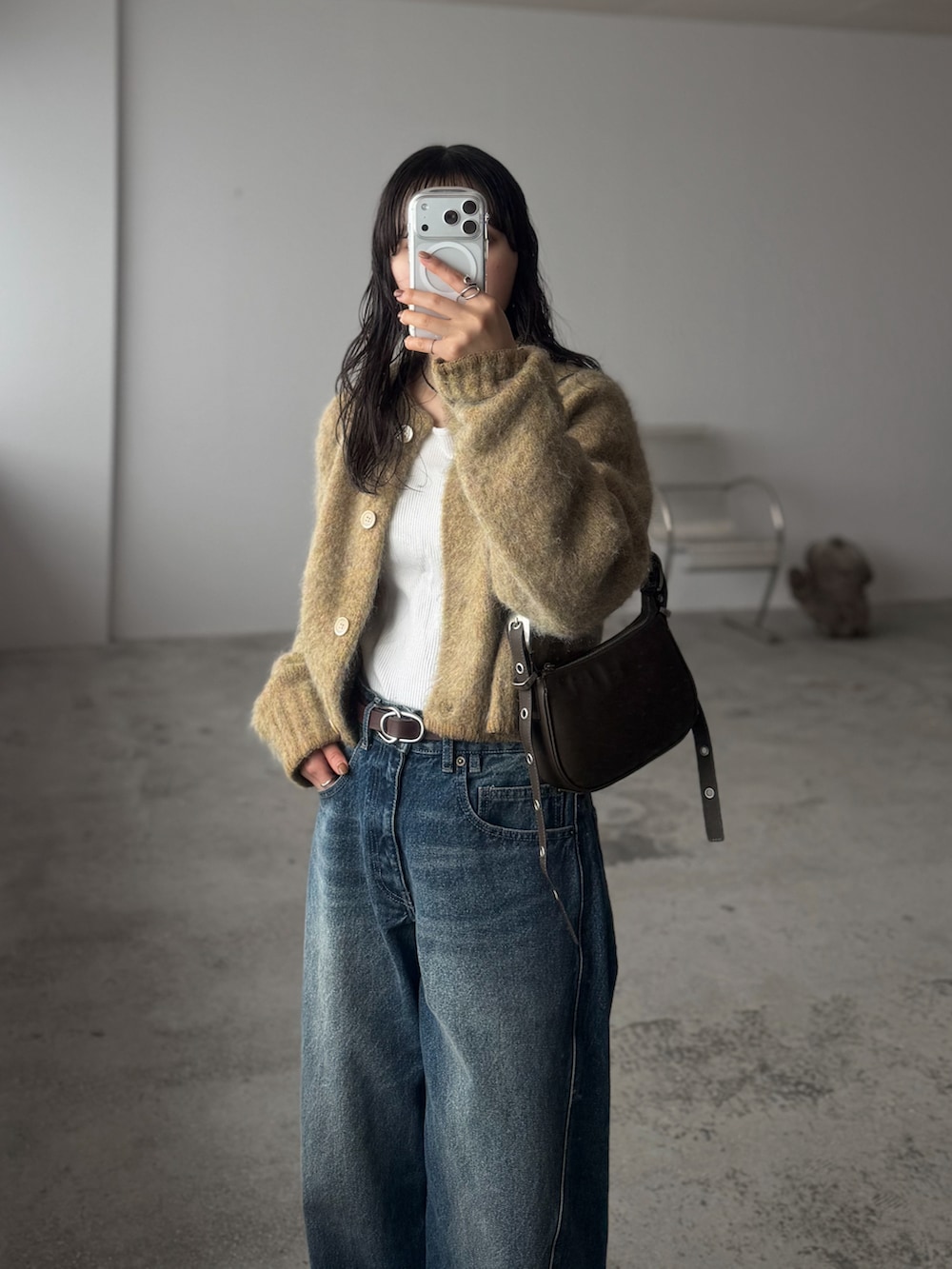 グリーン系のカーディガン/ボレロ、ホワイト系のニット/セーター、ブルー系のデニムパンツを着用したレディースの冬コーディネートの2枚目の写真