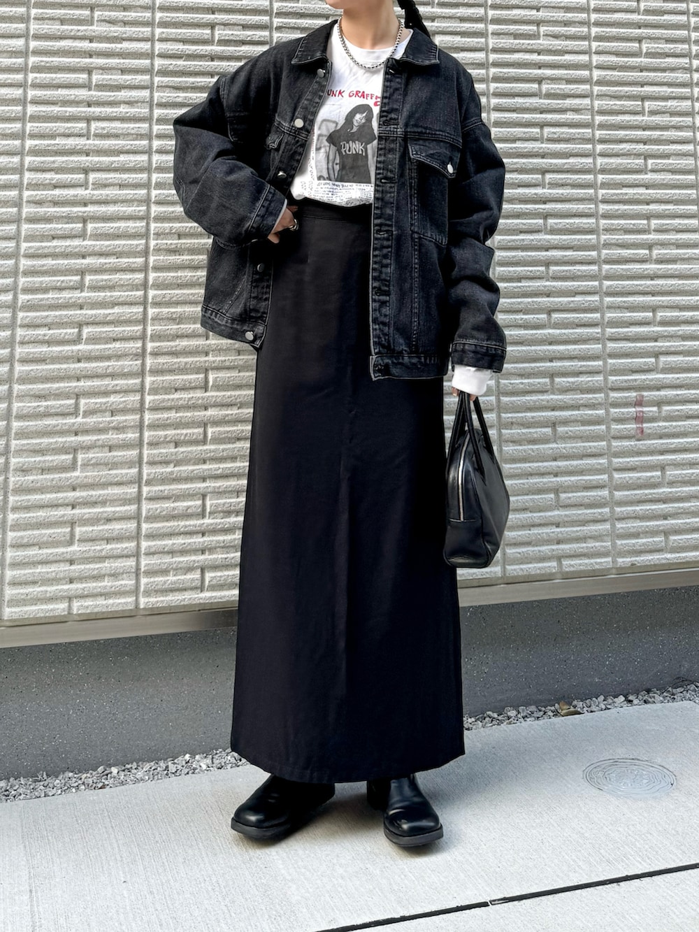 ブラック系のデニムジャケット、ホワイト系のTシャツ/カットソー、ブラック系のスカートを着用したレディースの冬コーディネートの2枚目の写真