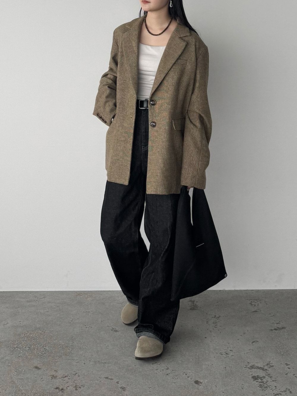 ブラック系のデニムパンツ、ベージュ系のテーラードジャケット、ベージュ系のサンダルを着用したレディースの秋コーディネートの2枚目の写真