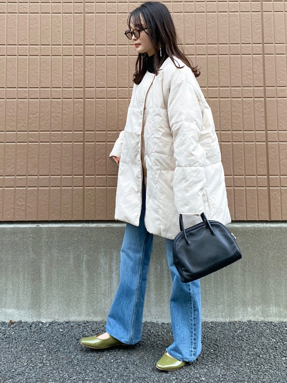ホワイト系のダウンジャケット/コート、ブルー系のデニムパンツ、ブラック系のショルダーバッグを着用したレディースの冬コーディネートの2枚目の写真