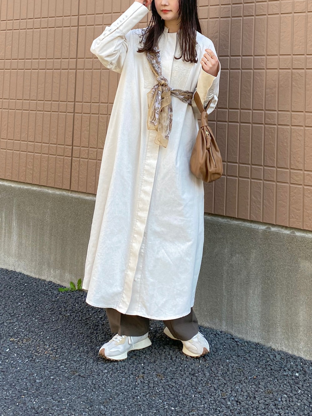 ブラウン系のスラックス、ブラウン系のバッグ、ホワイト系のスニーカーを着用したレディースの春コーディネートの2枚目の写真