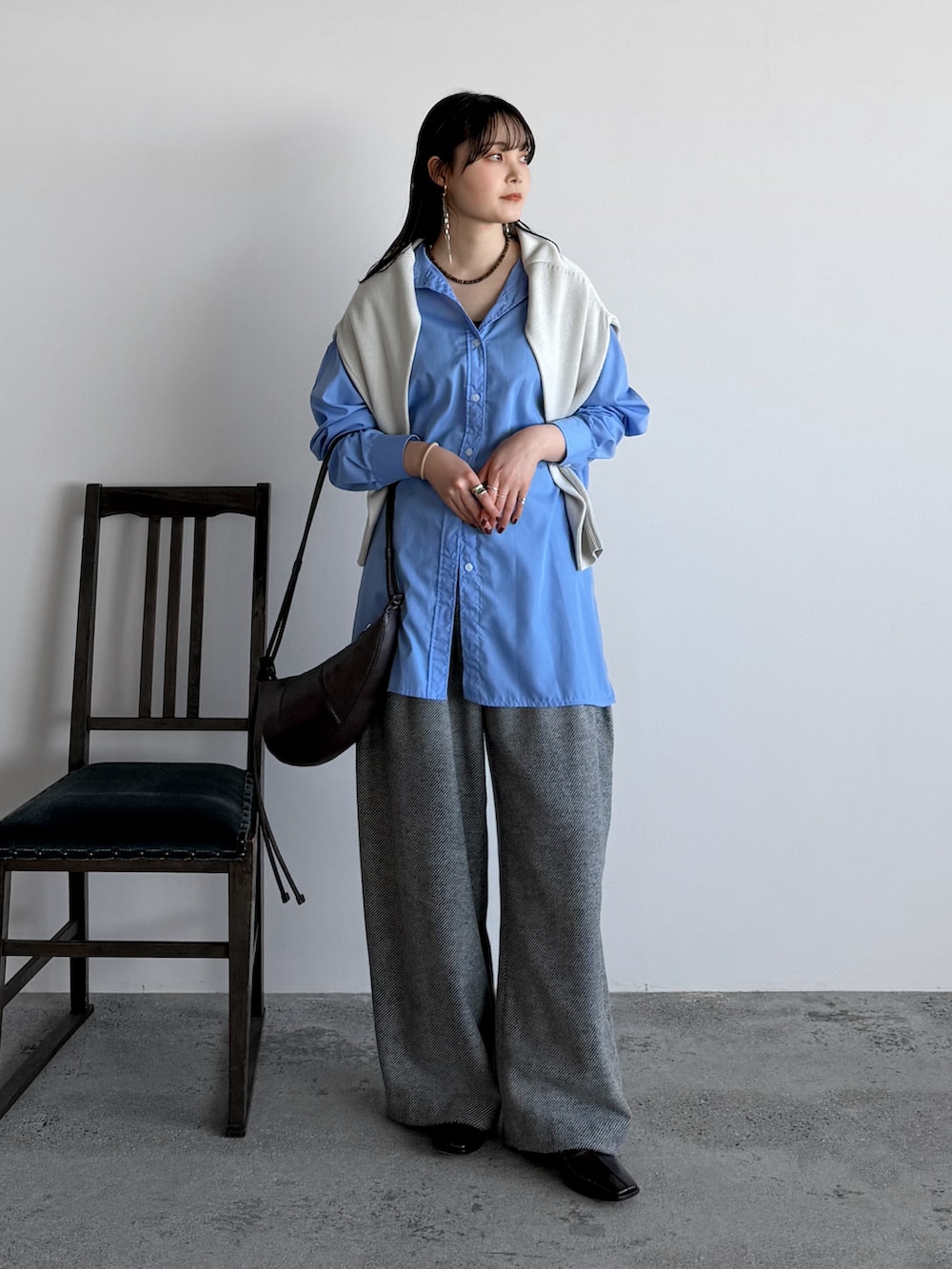 ブルー系のシャツ/ブラウス、ホワイト系のニット/セーター、グレー系のスラックスを着用したレディースの春コーディネートの2枚目の写真