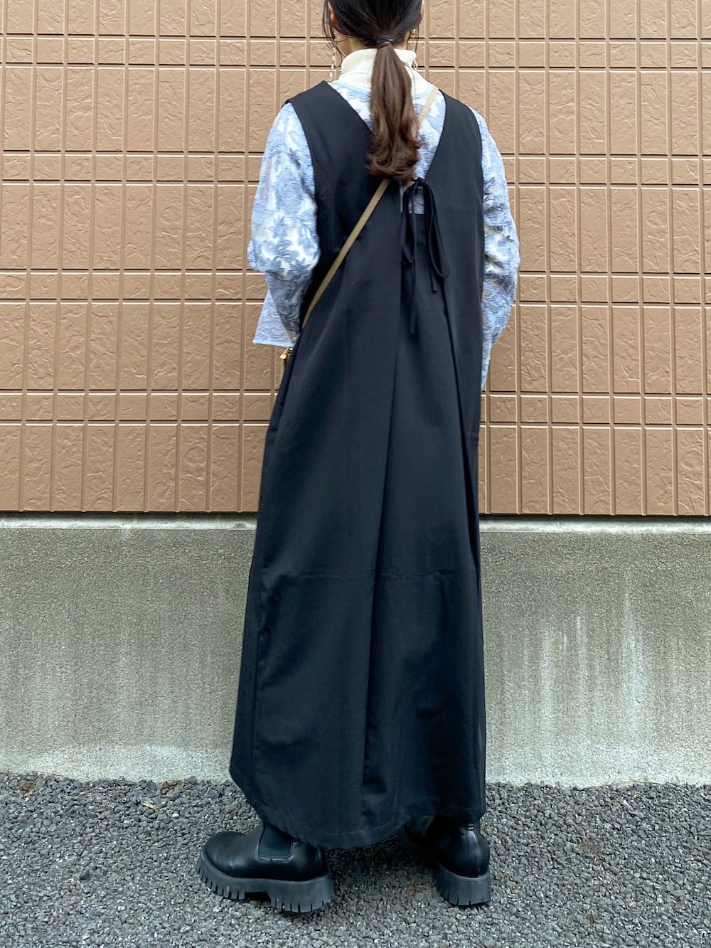 グレー系のシャツ/ブラウス、ブラック系のジャンパースカート、ホワイト系のニット/セーターを着用したレディースの冬コーディネートの3枚目の写真