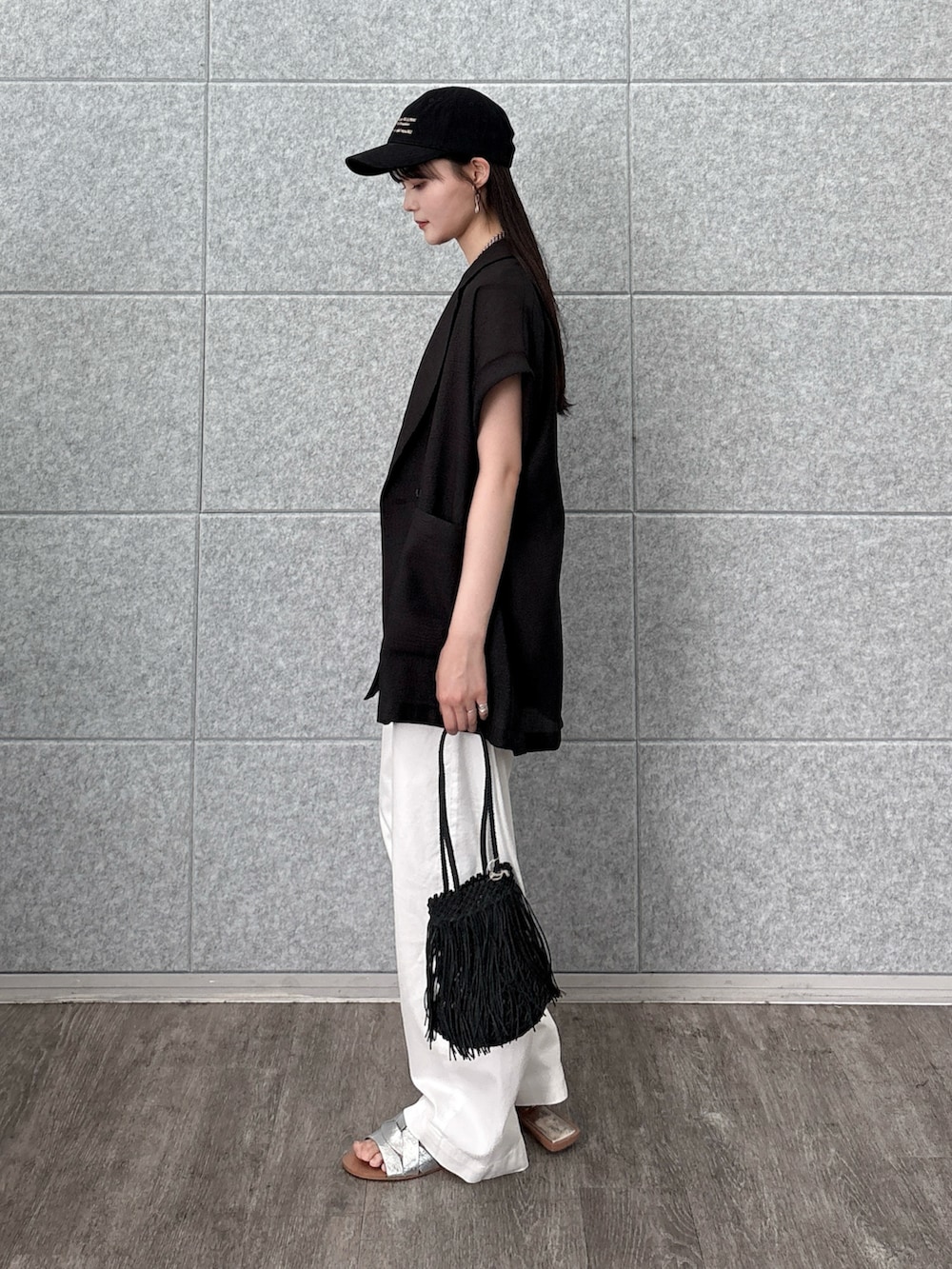 ブラック系のタンクトップ、ブラック系のテーラードジャケット、ホワイト系のデニムパンツを着用したレディースの夏コーディネートの3枚目の写真