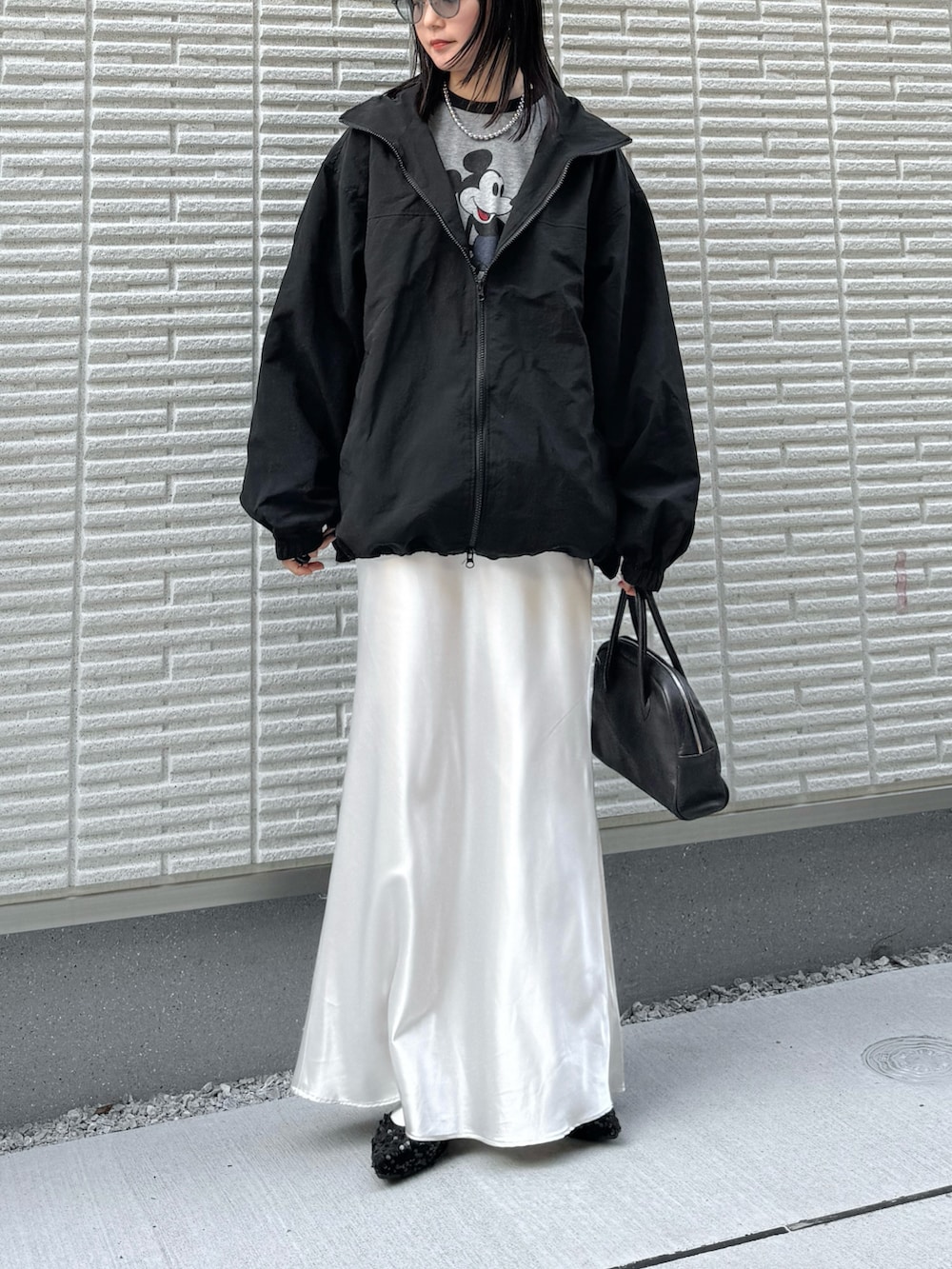 ブラック系のナイロンジャケット、グレー系のTシャツ/カットソー、ホワイト系のスカートを着用したレディースの春コーディネートの2枚目の写真