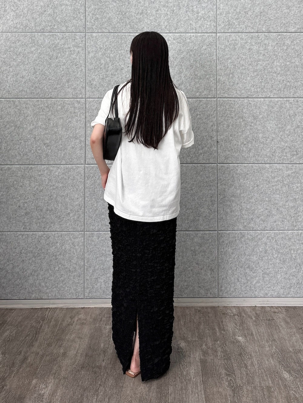 ブラック系のスカート、ホワイト系のTシャツ/カットソー、ブラック系のハンドバッグを着用したレディースの夏コーディネートの2枚目の写真
