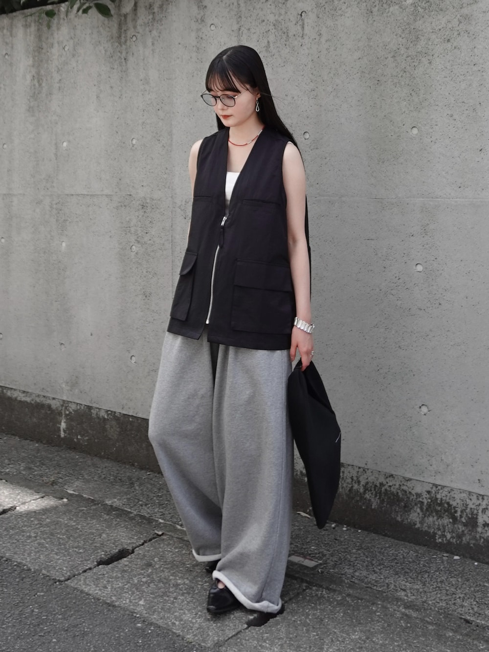 ブラック系のベスト、グレー系のスウェットパンツ、ブラック系のパンプスを着用したレディースの夏コーディネートの2枚目の写真