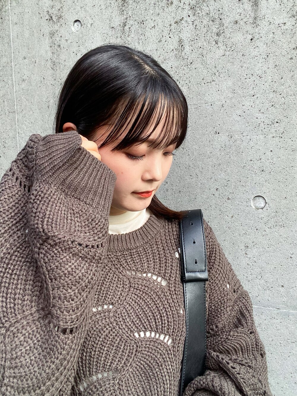 グリーン系のニット/セーター、グレー系のスラックス、ブラック系のショルダーバッグを着用したレディースの秋コーディネートの2枚目の写真