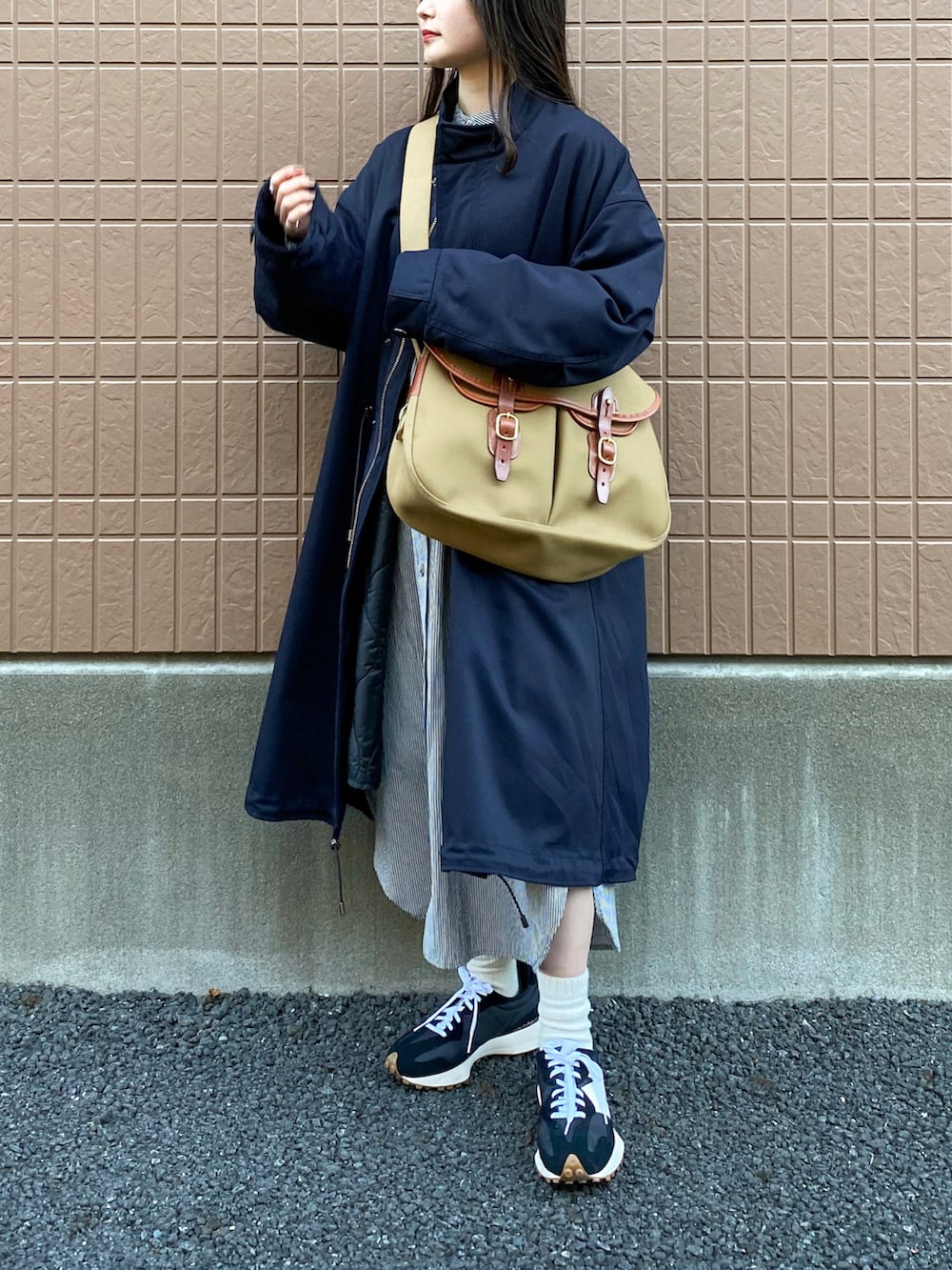 ブルー系のモッズコート、グリーン系のショルダーバッグ、ブラック系のスニーカーを着用したレディースの冬コーディネートの2枚目の写真