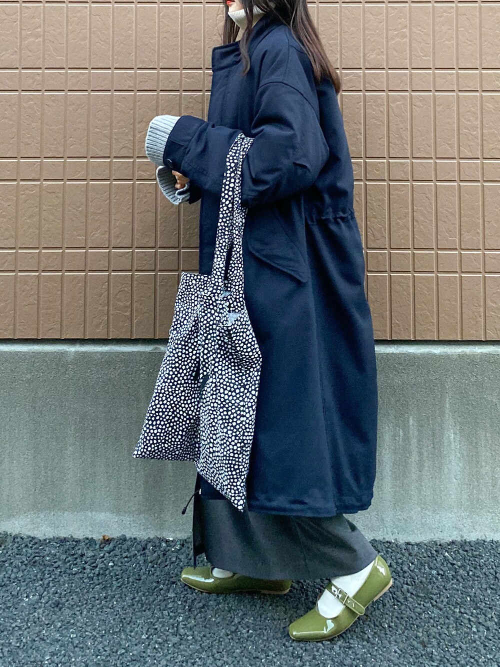 ブルー系のモッズコート、グレー系のニット/セーター、ベージュ系のワンピースを着用したレディースの冬コーディネートの2枚目の写真