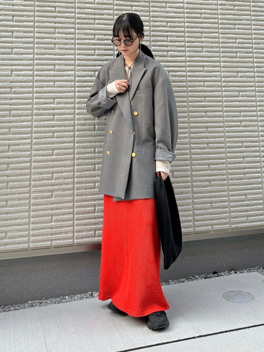 グレー系のテーラードジャケット、ホワイト系のニット/セーター、レッド系のスカートを着用したレディースの春コーディネートの2枚目の写真