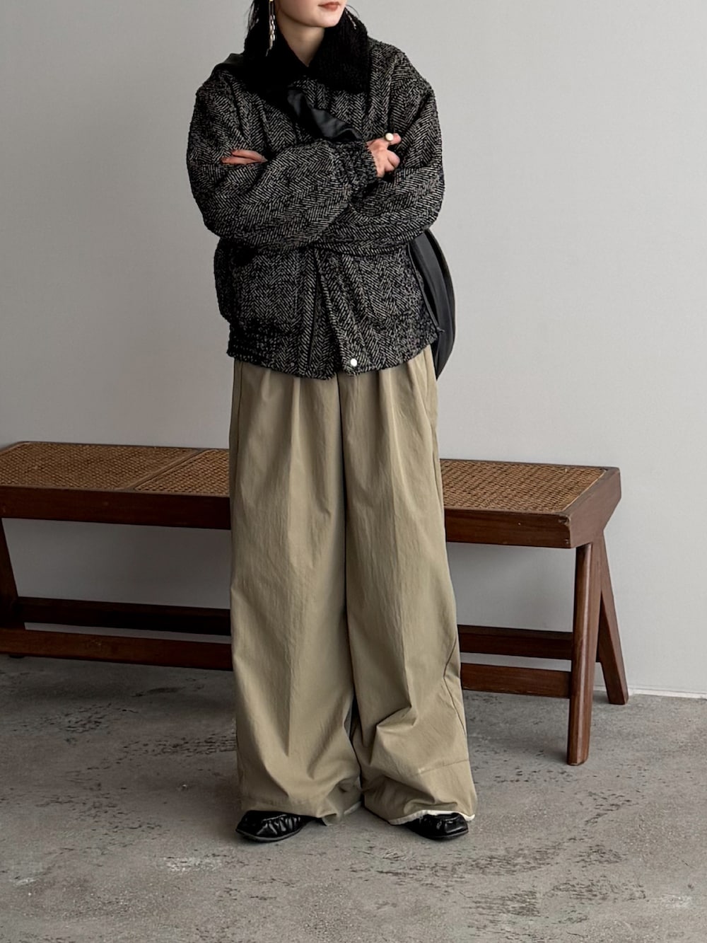 ベージュ系のスラックス、グレー系のブルゾン、ブラック系のショルダーバッグを着用したレディースの冬コーディネートの2枚目の写真