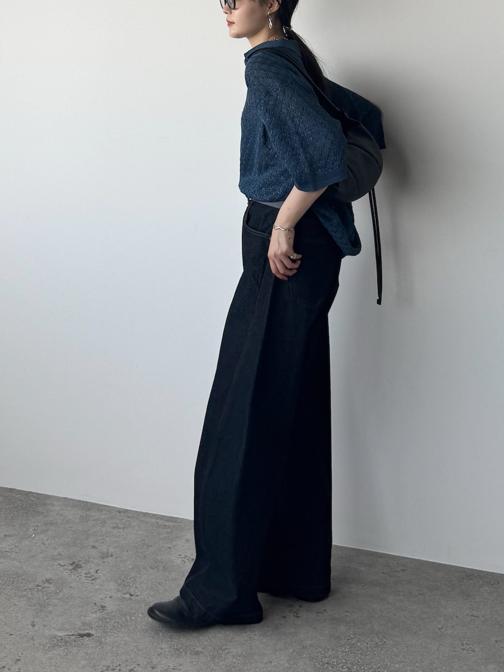 ブルー系のポロシャツ、ブルー系のデニムパンツ、ブラック系のショルダーバッグを着用したレディースの夏コーディネートの2枚目の写真