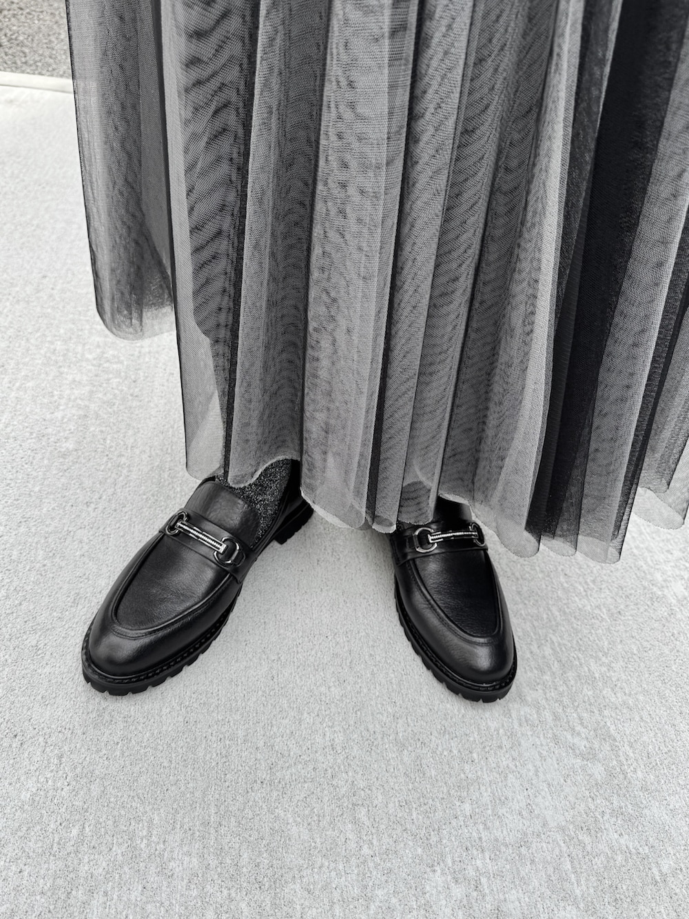 ブラック系のローファー、グレー系のナイロンジャケット、ブラック系のスカートを着用したレディースの冬コーディネートの2枚目の写真